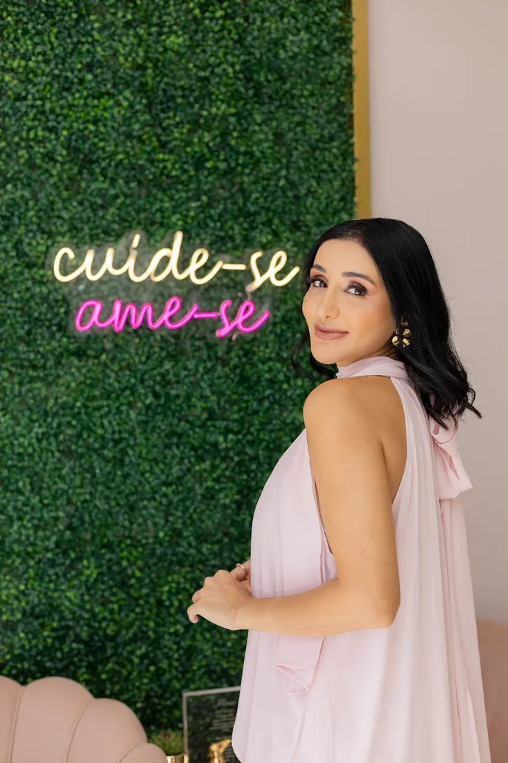 Ludmilla Oliveira em frente à parede verde da clínica