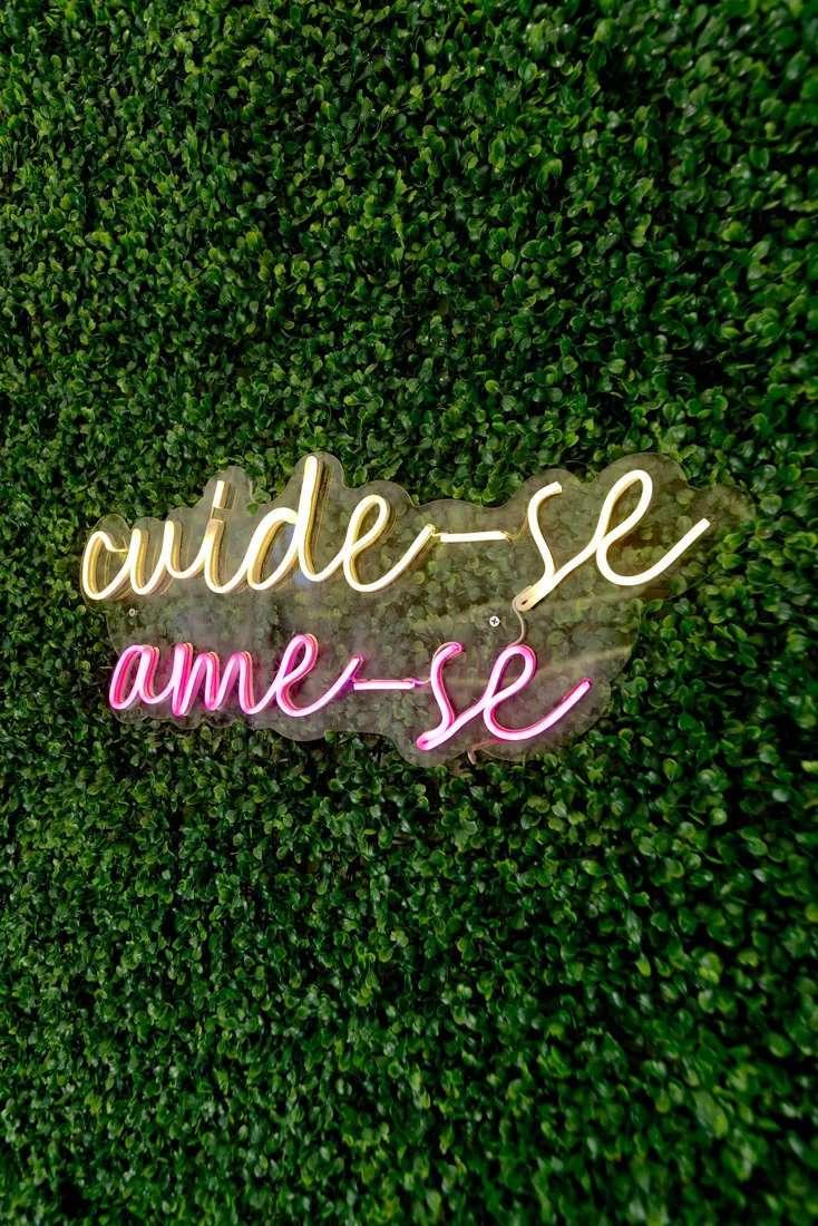 Letreiro em neon com as frases cuide-se e ame-se sobre parede verde